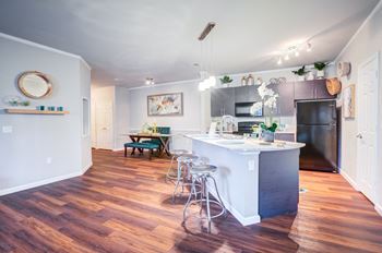 A kitchen with a white island and wooden floors.